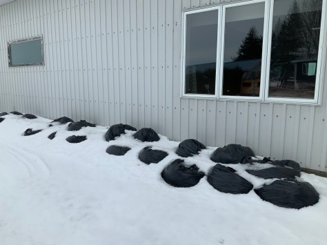 Photo Sacs de poubelles le long du garage municipal durant l'hiver