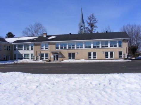 Face arrière de l'école primaire Arc-en-Ciel et clocher d'église